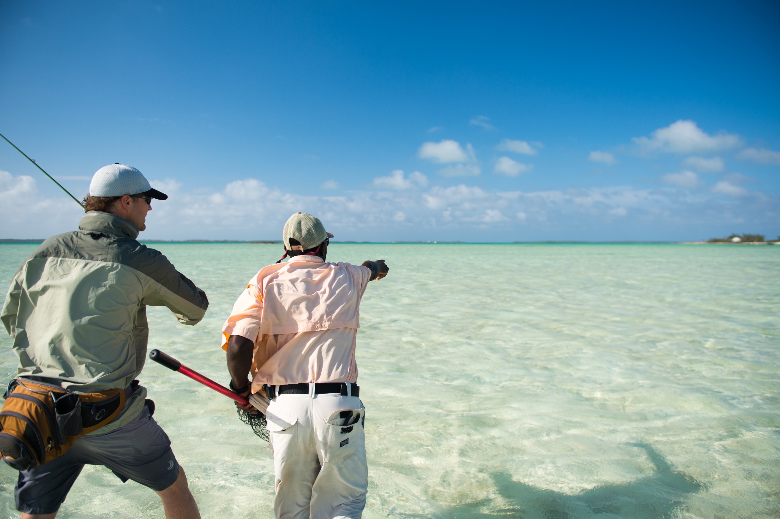 A guide points out a bonefish to an angler in the Bahamas.