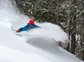 A skier carving hard and creating a cloud of snow.