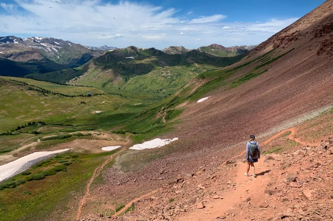 A hiker headed down a rocky hill in the Rockies.