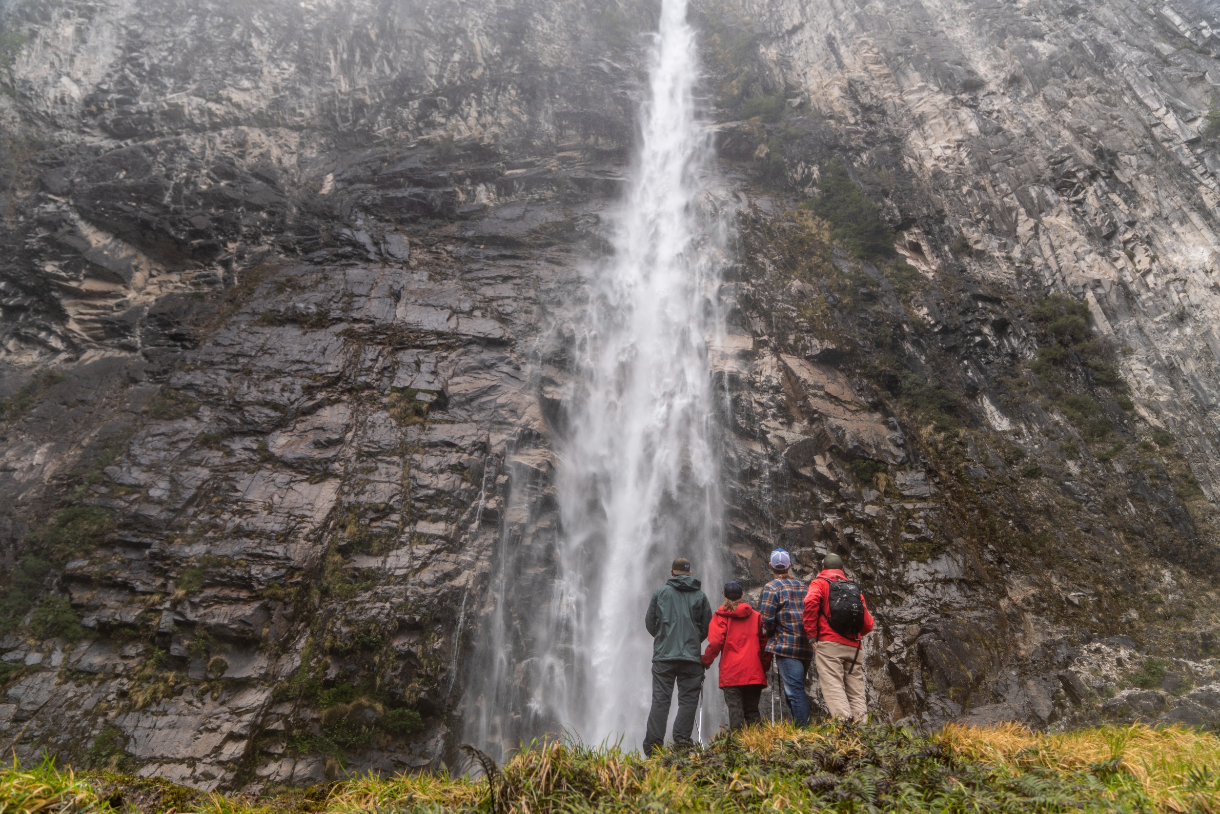 A gourp of people standing in front of a Patagonian waterfall.