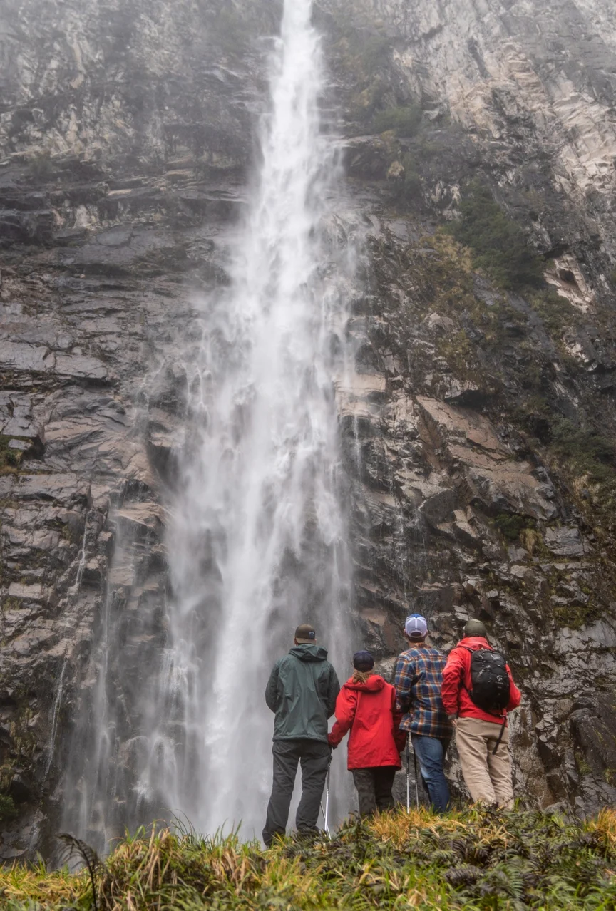 A gourp of people standing in front of a Patagonian waterfall.