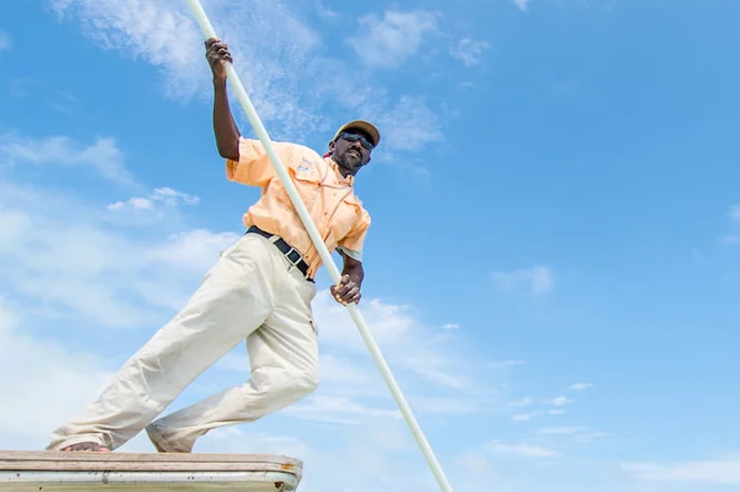 A bonefishing guide poles a skiff in the Bahamas.