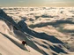 A person skiing at dusk above the clouds.