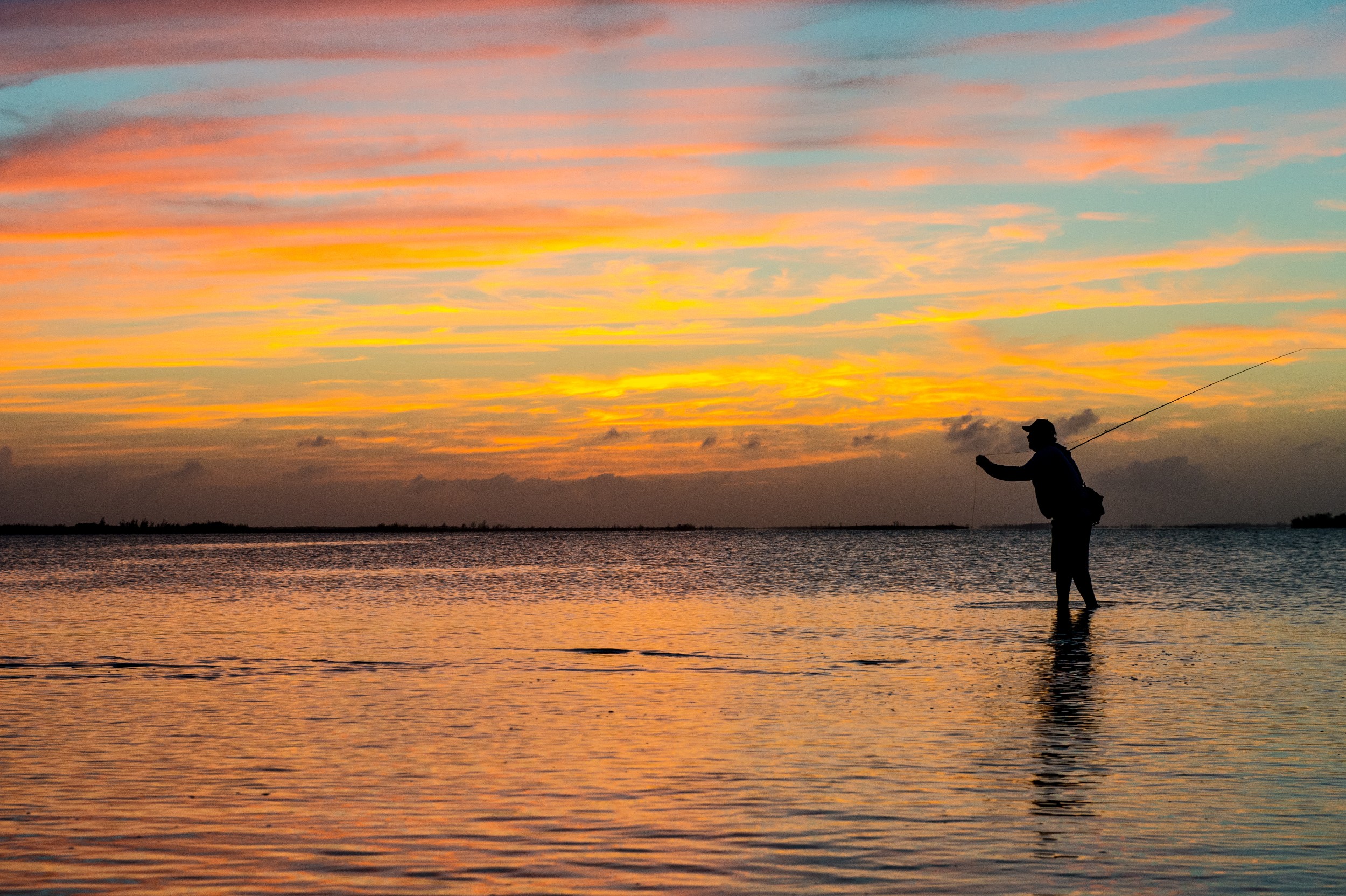 An angler makes a cast at sunset in the Bahamas.