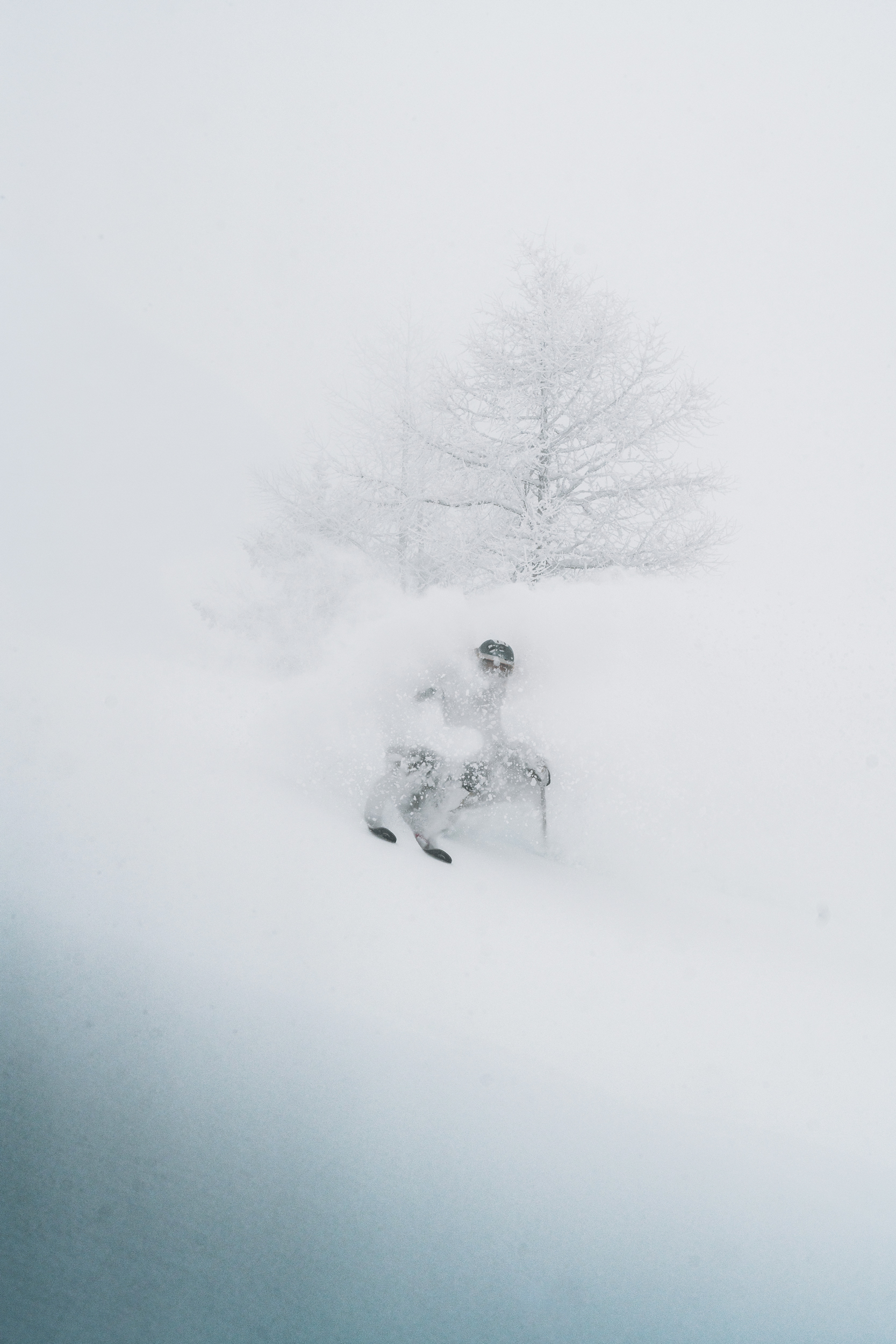 A skier in a cloud of snow headed down a near vertical slope.
