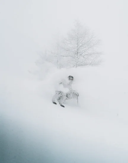 A skier in a cloud of snow headed down a near vertical slope.