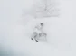 A skier in a cloud of snow headed down a near vertical slope.