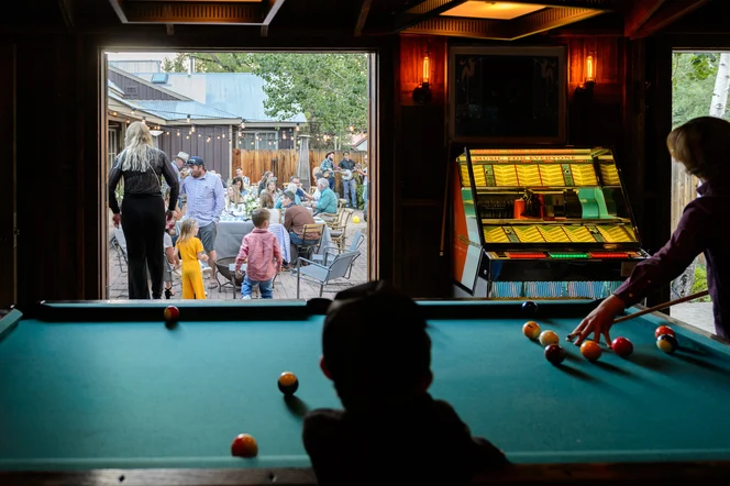 People playing pool next to an outdoor event space with live music and drinks.