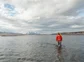 A man walking through knee deep water in a lake in Iceland.