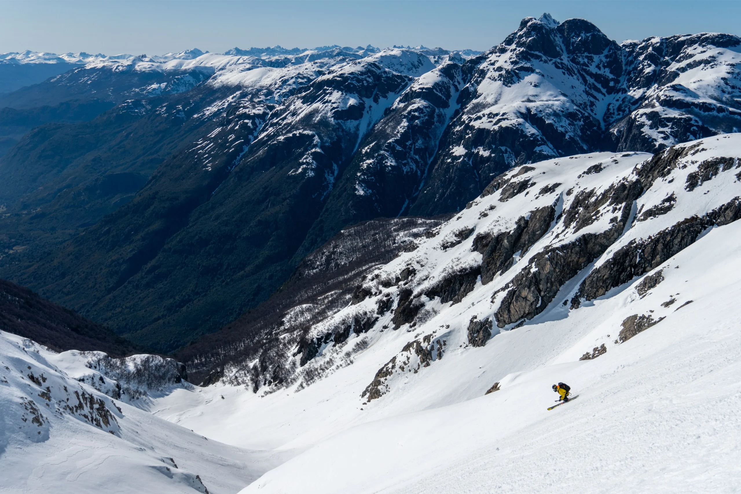 A person skiing down a mountain with a wide view of the mountains in Patagonia.