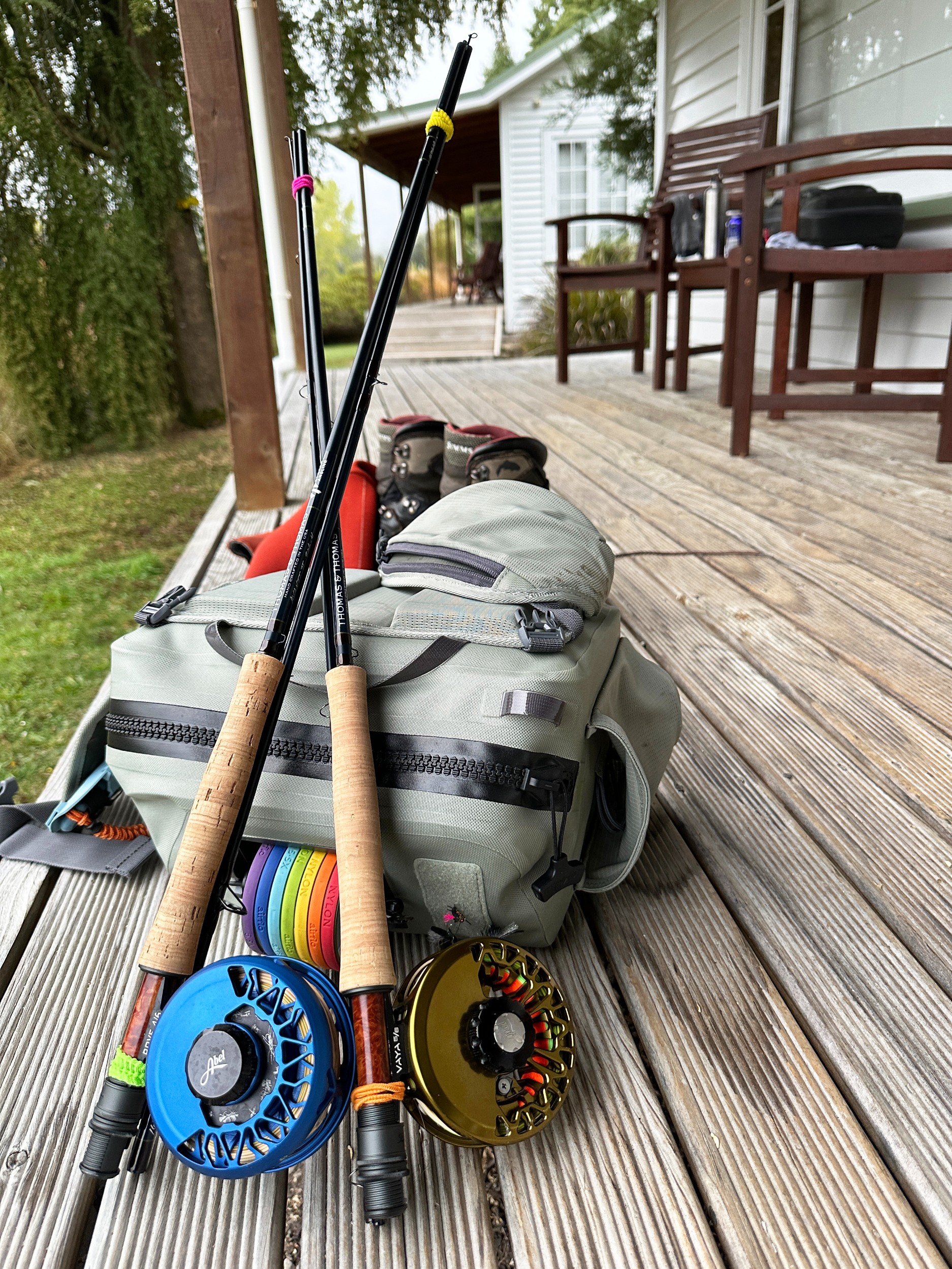 A close up of two fishing poles and reels and a back pack full of fishing equipment.