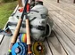 A close up of two fishing poles and reels and a back pack full of fishing equipment.