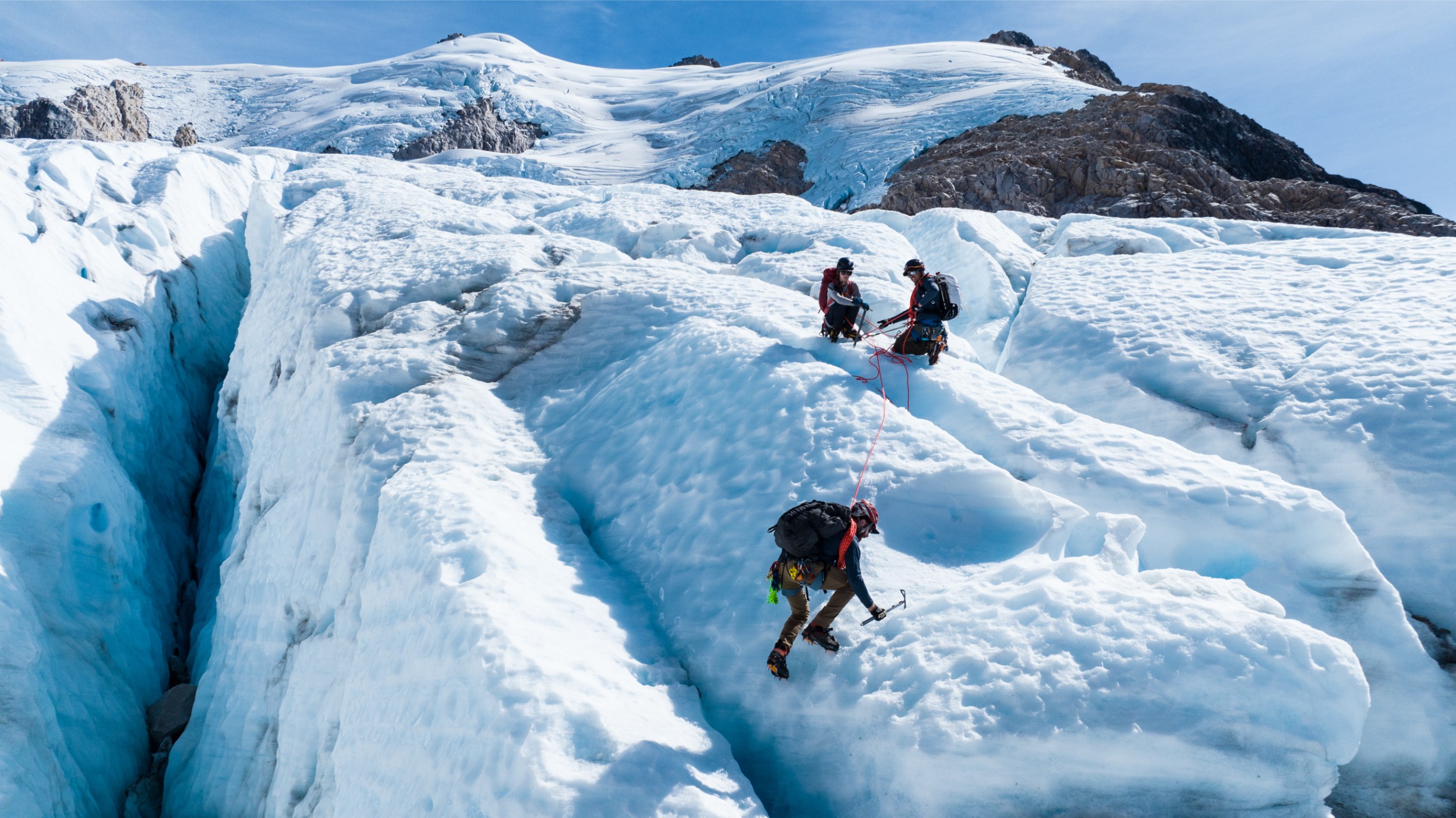 A group of climbers using ice picks to cross a glacier in Chile.