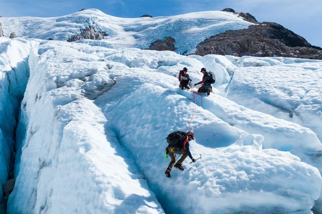 A group of climbers using ice picks to cross a glacier in Chile.