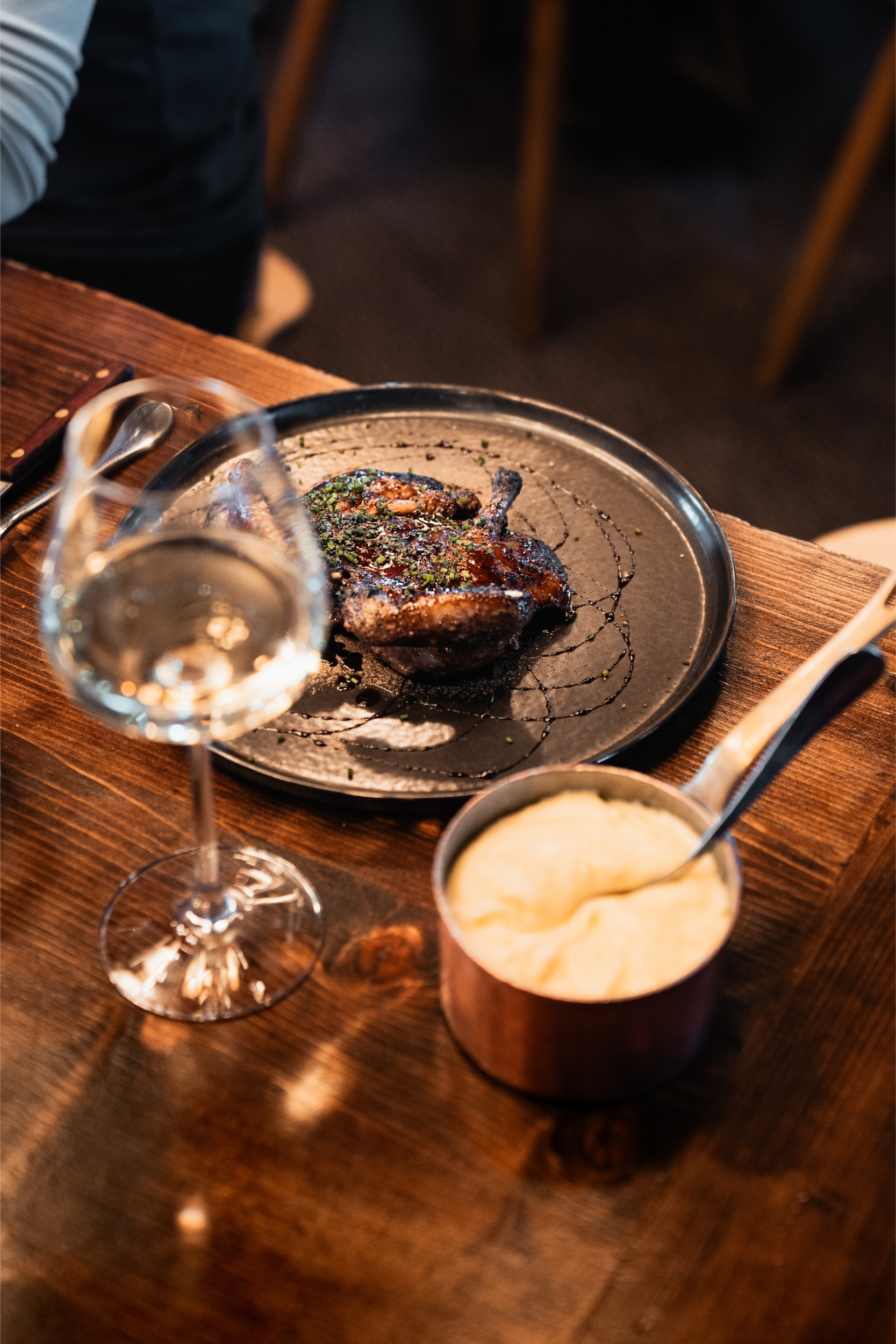 A plated roast chicken with mash potatoes and a glass of wine.
