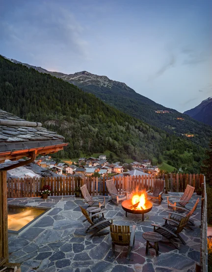 A patio with a fire pit overlooking a mountain valley and small village.