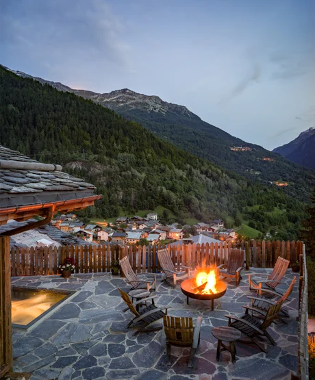 A patio with a fire pit overlooking a mountain valley and small village.