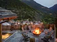 A patio with a fire pit overlooking a mountain valley and small village.