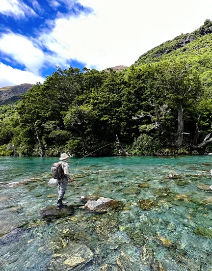 man fishing on rocks by mountainside