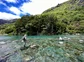 man fishing on rocks by mountainside