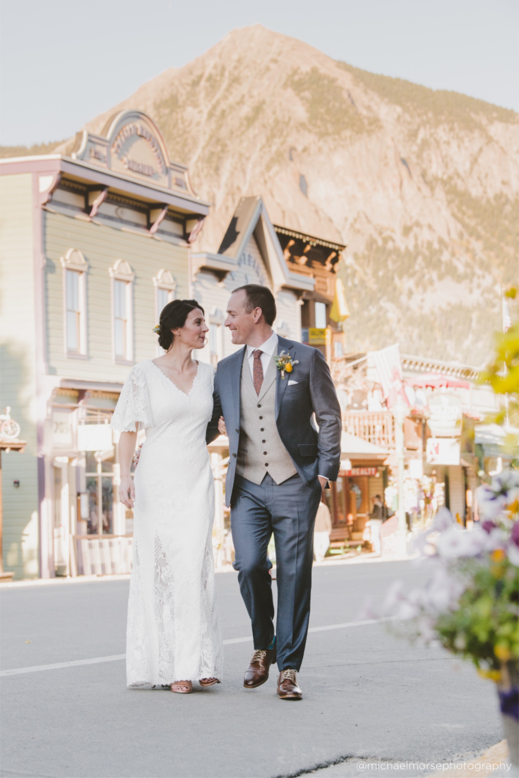 Newlywed husband and wife walking down street in Crested Butte in their dress and suit.