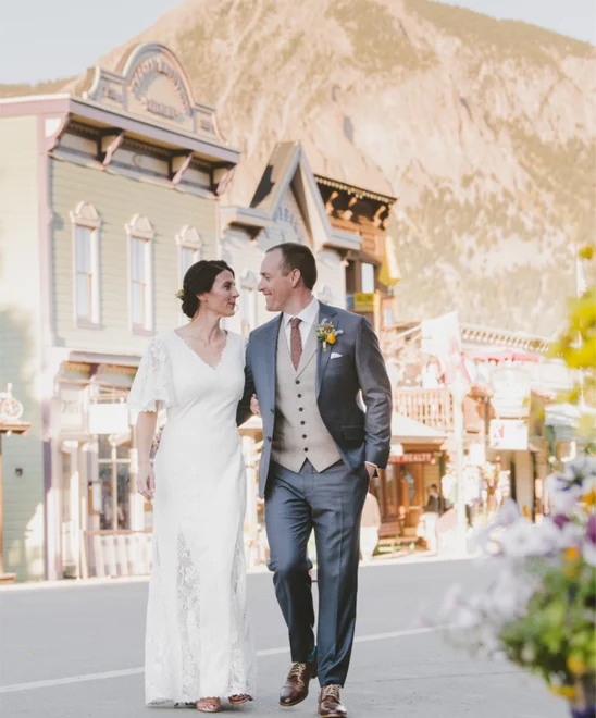 Newlywed husband and wife walking down street in Crested Butte in their dress and suit.