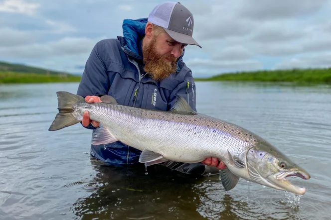 A fisher holding a large atlantic salmon.