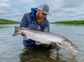 A fisher holding a large atlantic salmon.