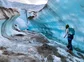 A person walking along a large formation of a glacier.