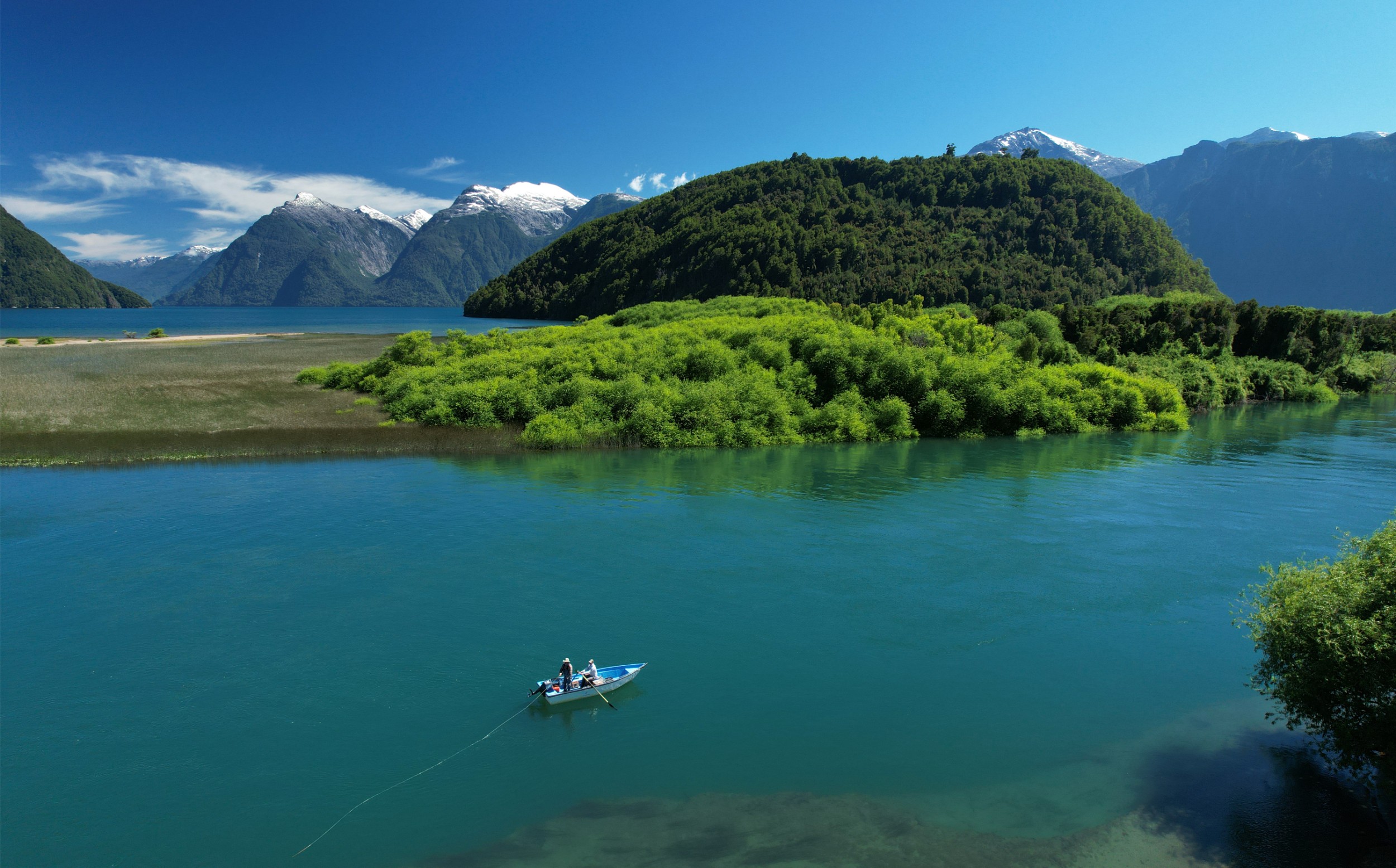 People fly fishing on a small boat on a river in Patagonia.