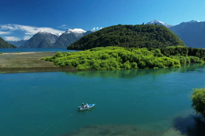 People fly fishing on a small boat on a river in Patagonia.