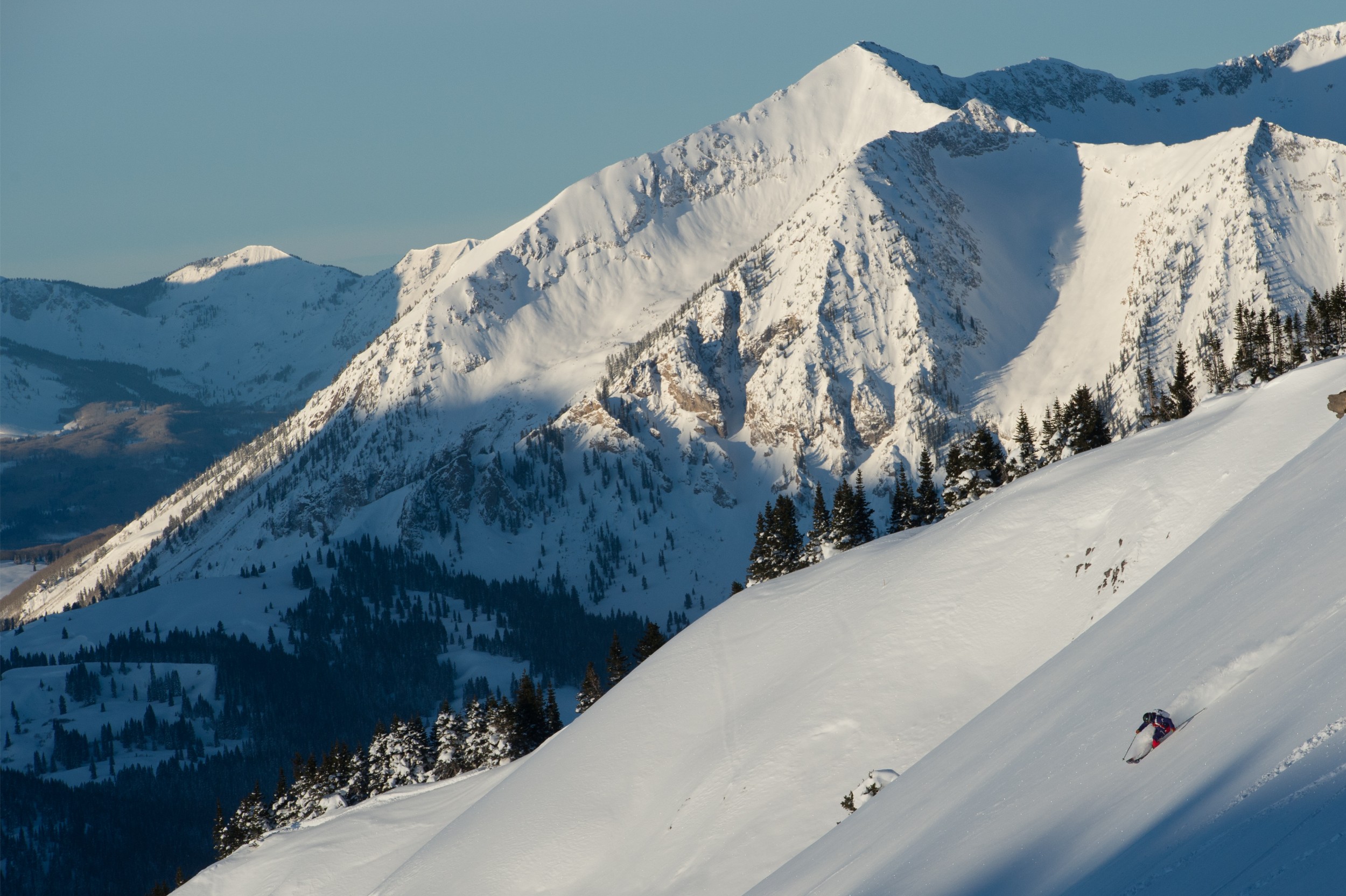 A person skiing down a steep slope terrain in the Rockies.