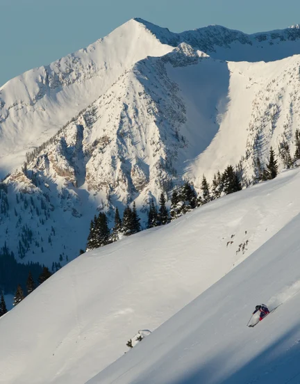 A person skiing down a steep slope terrain in the Rockies.