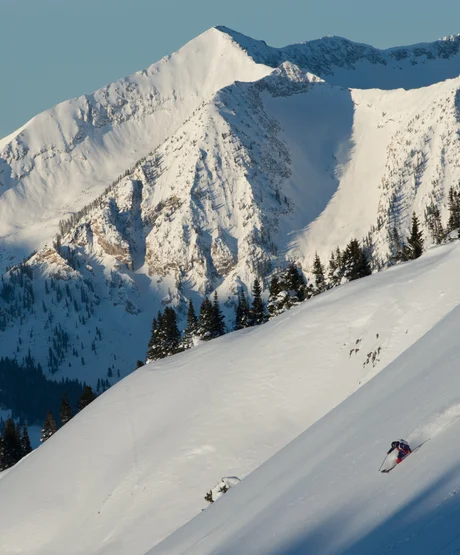 A person skiing down a steep slope terrain in the Rockies.