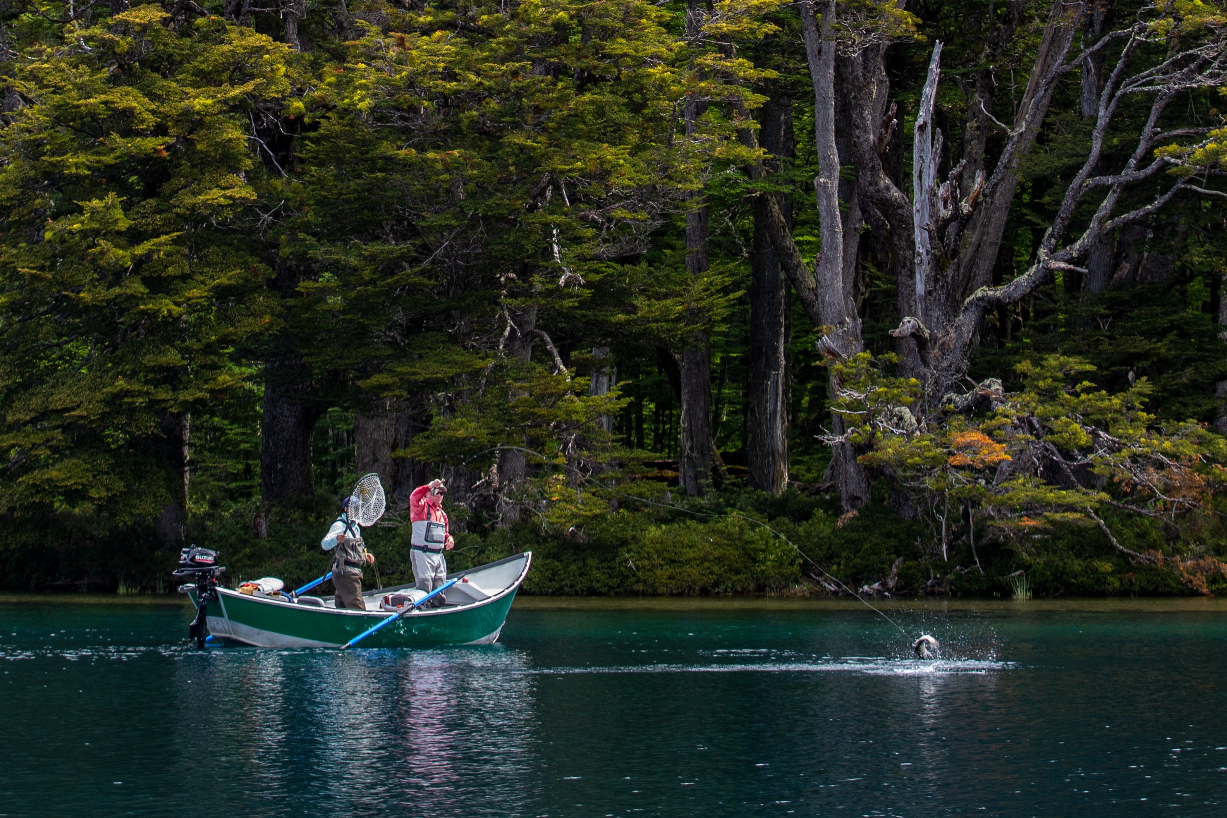 Two fishers on a small boat catching a fish in Chile.