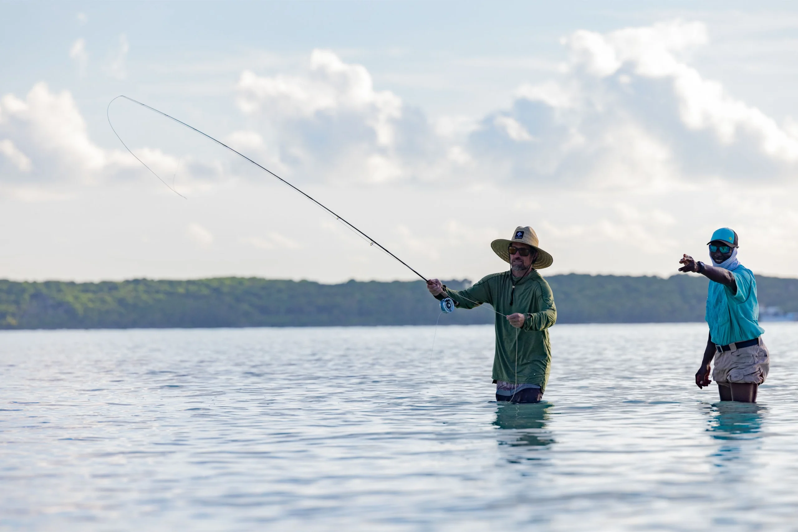 An angler fishes while a guid points out where to cast.
