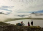 Three bikers overlooking a lake surrounded by mountains in Iceland.