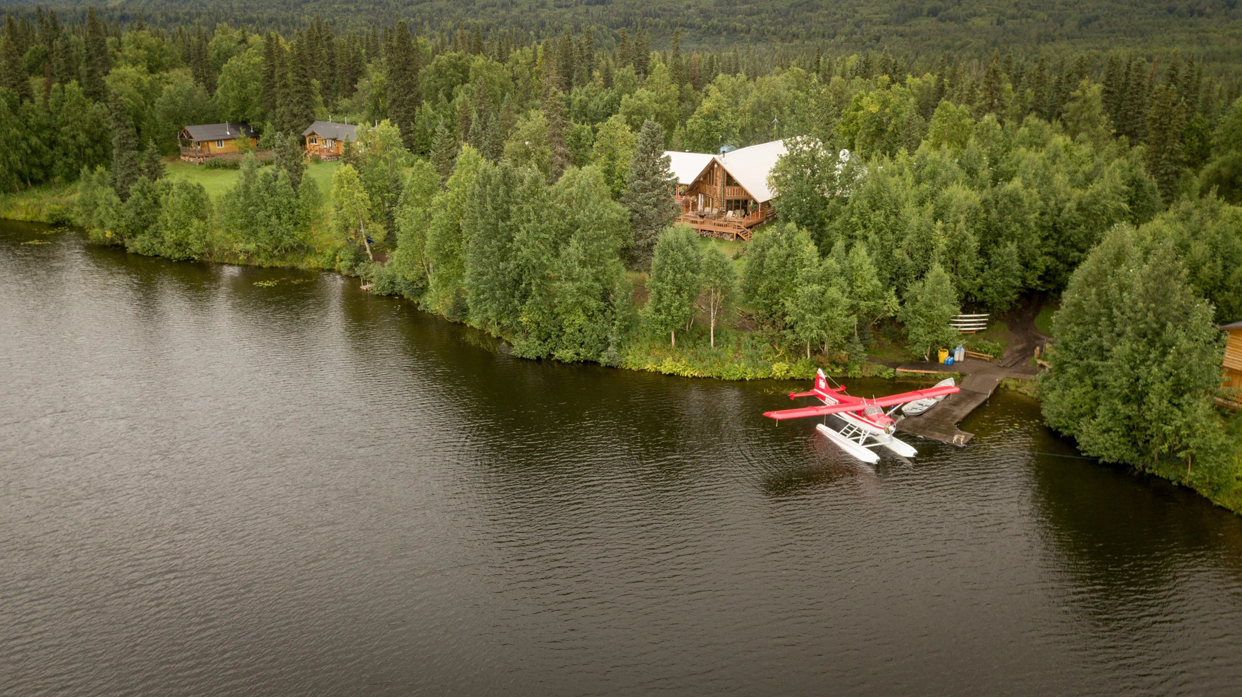 Exterior of a log cabin, Eleven Winterlake Lodge, surrounded by trees with a lake in front.