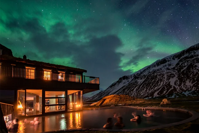 People enjoying the heated outdoor pool with the Northern Lights overhead.