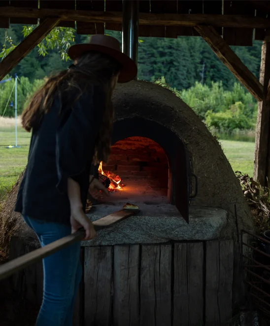 Chef putting food into a wood-fired oven.