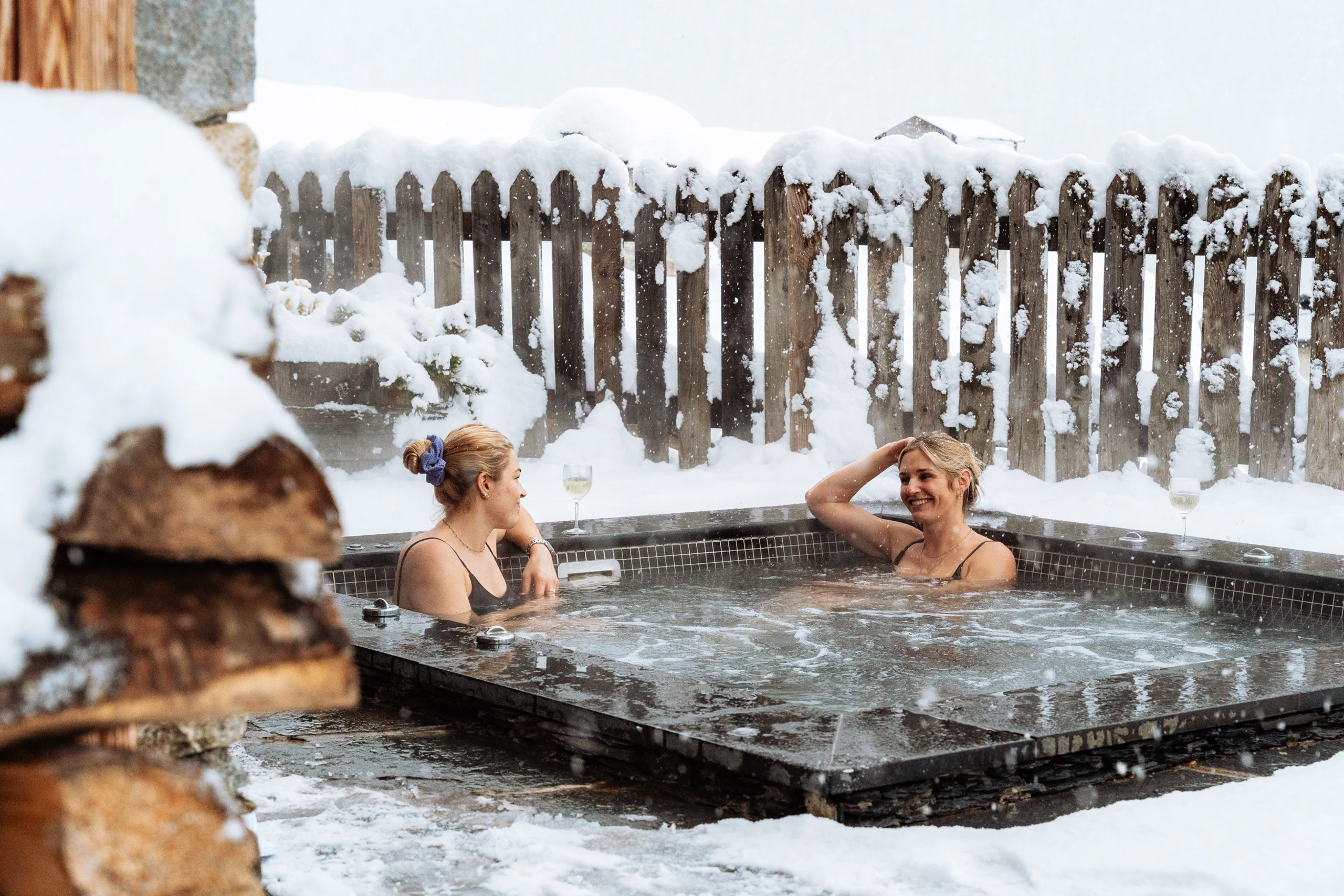 A group of people in an outdoor hot tub with a view of the snow covered alps.