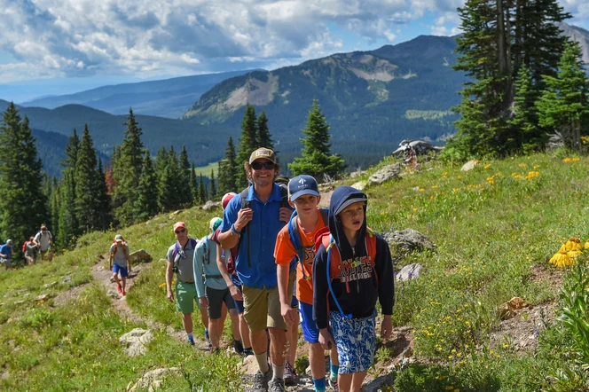 A happy guide and a couple families walking a mountain trail in Colorado