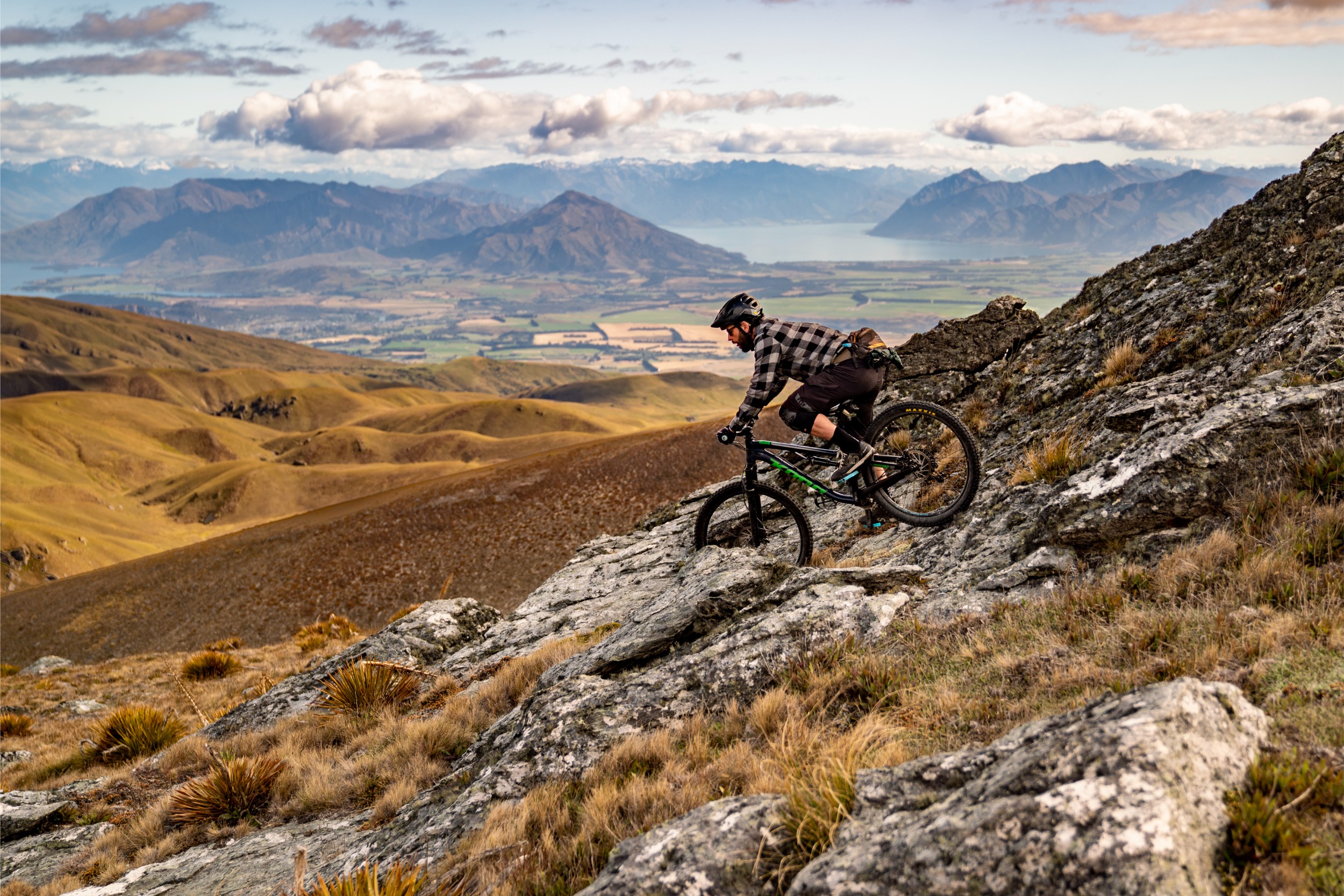 A biker barreling down a rocky trail on a mountain in New Zealand.