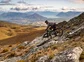 A biker barreling down a rocky trail on a mountain in New Zealand.