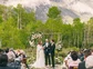 A soon-to-be husband and wife exchanging vows at their wedding ceremony and a mountain in in the distance.