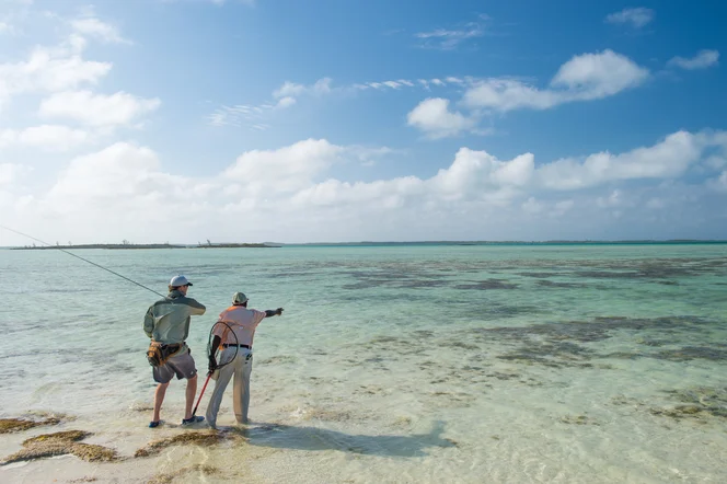 A guide points out a fish to an angler in the Bahamas.