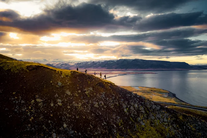 A group of hikers walking on a mountain ridge at dusk.
