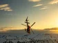 A helicopter over snow mountains performing an aerial maneuver.