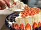 A cake with kiwi, and strawberries being cut and served.