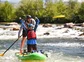A guide and a child learning how to ride a stand up paddle board.